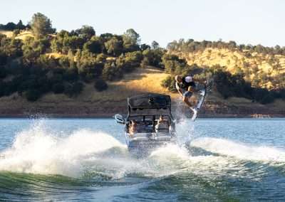 Man wakeboarding behind speeding boat on lake